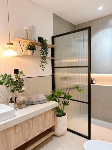 a bathroom with a shower with plants and a sink at Naomi Nala Villa Bandung in Gantungan