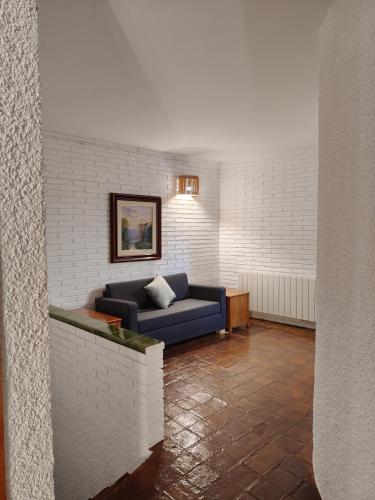 a living room with a blue couch in a brick wall at Casa rural entera en Parque Natural de los Puertos in Alfara de Carles
