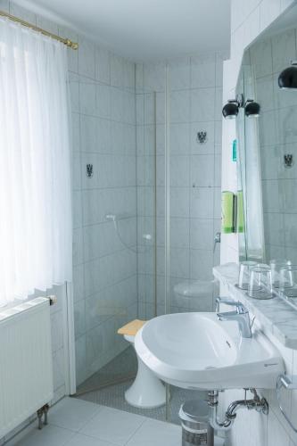 a white bathroom with a sink and a shower at Hotel & Restaurant Mainaublick in Uhldingen-Mühlhofen