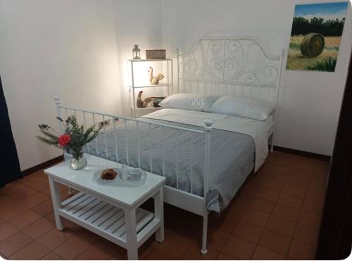 a bedroom with a white bed and a table at Casale Traiano in Fiumicino