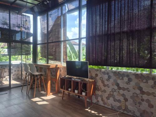 a living room with a tv and a table and windows at The Paica in Denpasar