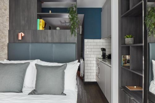 a bedroom with a white bed and a blue wall at ARK Canary Wharf in London