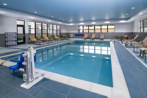 a pool in a hotel with tables and chairs at Hyatt House Auburn Hills/Detroit in Lake Orion