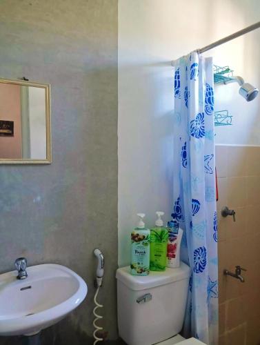 ein Badezimmer mit Waschbecken, Toilette und Duschvorhang in der Unterkunft NM Homestay in Tayabas