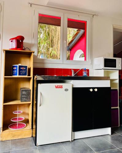 La cuisine est équipée d'un réfrigérateur blanc et d'un four micro-ondes. dans l'établissement La petite maison rouge, à Cucq