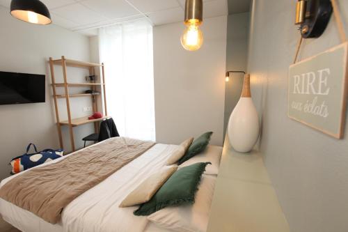 a bedroom with a large bed with green pillows at Cit'Hotel Les Alizes in Dinard