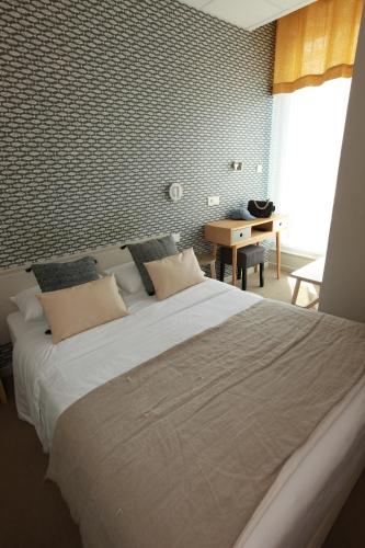 a bedroom with a large bed and a desk at Cit'Hotel Les Alizes in Dinard