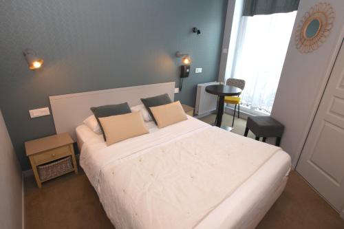a bedroom with a large white bed with two pillows at Cit'Hotel Les Alizes in Dinard