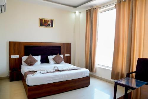 a bedroom with a bed and a window and a table at Hotel Thames Zirakpur Chandigarh Highway in Zirakpur