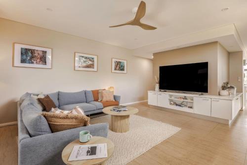 a living room with a blue couch and a flat screen tv at Salty Solstice-Beachside Dunsborough Town in Dunsborough