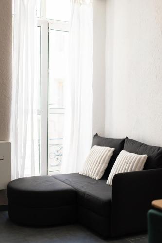 un canapé noir dans un salon avec une fenêtre dans l'établissement Nîmes centre, à Nîmes