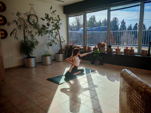 a woman doing a yoga pose in a room with windows at Pohorje Village Wellbeing Resort - Forest Hotel Videc in Pohorje
