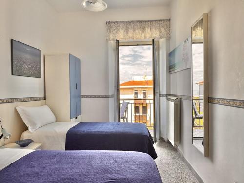 a hotel room with two beds and a balcony at Holidaycasa Robert - Eleganza e comfort sul mare in Sperlonga