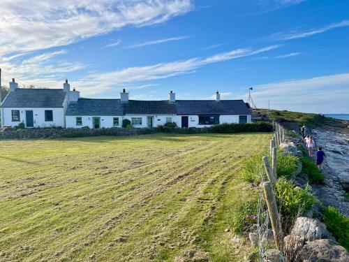 a house on the beach with a field in front at Bungalow by the Sea, Moelfre in Moelfre