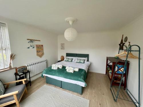 a bedroom with a green bed and a couch at Bungalow by the Sea, Moelfre in Moelfre