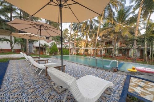 a resort with a pool with chairs and umbrellas at Echor La Blanca Resort Mandrem Goa in Mandrem