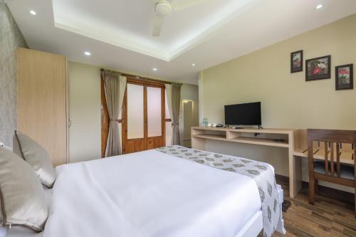 a bedroom with a white bed and a television at Echor La Blanca Resort Mandrem Goa in Mandrem