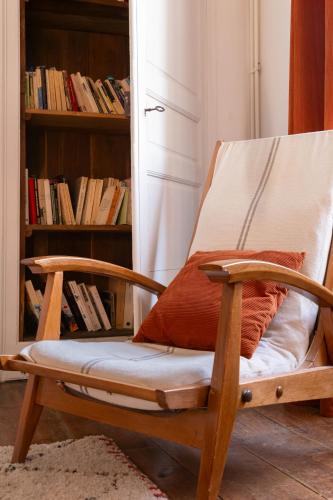 a wooden rocking chair in a room with a book shelf at Artefact in Lamballe