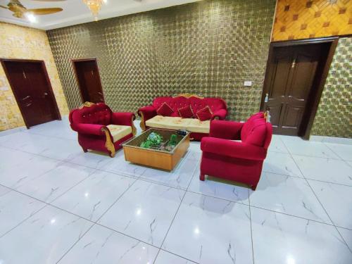 a living room with red chairs and a coffee table at Hotel PAK Continental Multan in Multan