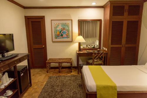 a bedroom with a bed and a desk and a television at Oasis Hotel in Angeles