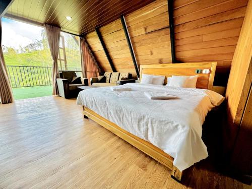 a bedroom with a large bed and a large window at Solitary Green Cabins in Lindula