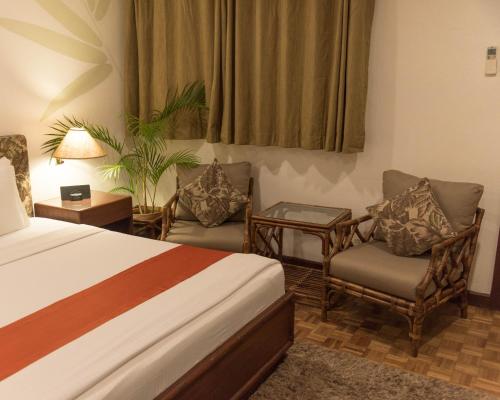 a hotel room with a bed and two chairs at Oasis Hotel in Angeles