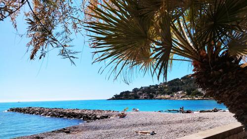- une plage avec des personnes sur le sable et l'eau dans l'établissement Proche mer charmant appartement, à Roquebrune-Cap-Martin