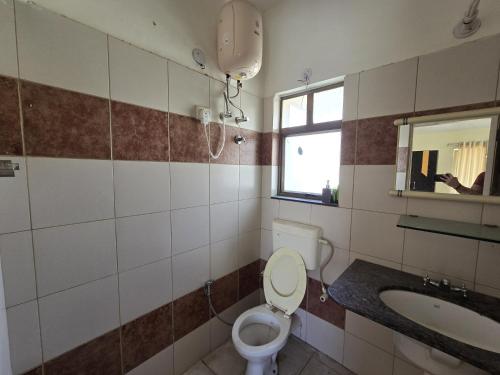 a bathroom with a toilet and a sink and a window at Blue Haven Villa - Luxurious 3BHK Stay in Jodhpur