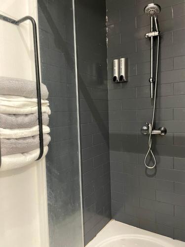 La salle de bains est pourvue d'une douche avec une porte en verre et de serviettes. dans l'établissement Chez Louis, à Saint-Flour