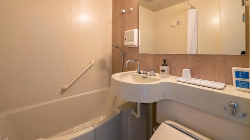a bathroom with a sink and a toilet and a mirror at Toyoko Inn Kobe Sannomiya Ekimae in Kobe