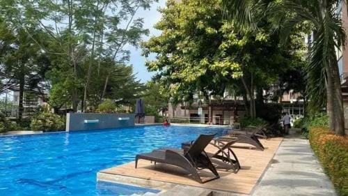 a swimming pool with chaise lounge chairs and trees at Matina Enclaves 1 bedroom in Davao City