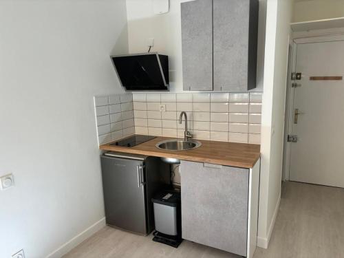 une petite cuisine avec un évier et un réfrigérateur dans l'établissement Studio Meublé Toulouse, à Toulouse