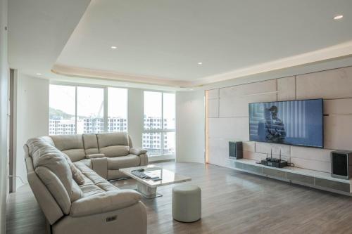 a living room with a couch and a flat screen tv at 1BR Luxury The City Phuket in Ban Ket Ho