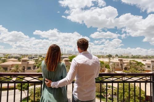 a couple standing on a balcony looking out at the city at LEscapade at St Regis Saadiyat in Abu Dhabi