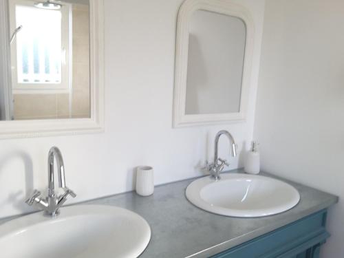a bathroom with two sinks and a mirror at Maison proche du Bassin d'Arcachon in Salles