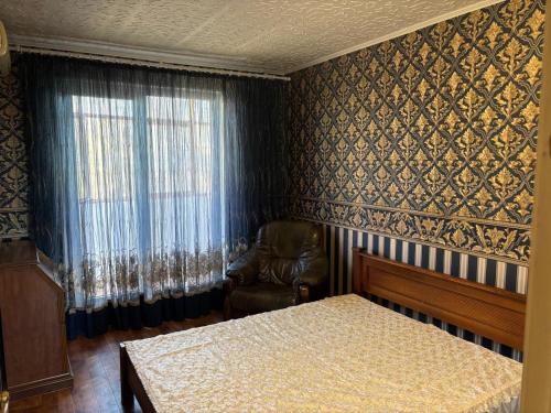 Un dormitorio con una cama y una silla y una ventana. en Джакузи! Двухкомнатная квартира, Героев Труда Французкий, бульвар,Барабашово, en Járkov