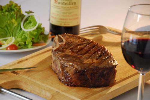 a steak on a wooden cutting board with a glass of wine at Oasis Hotel in Angeles