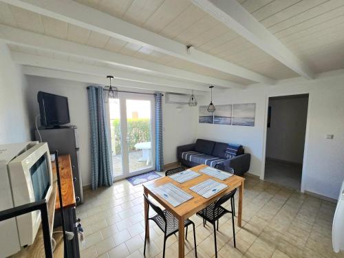 un salon avec une table et un canapé dans l'établissement SANTOLINES : Charmante maisonnette avec piscine proche Etang, à Marseillan