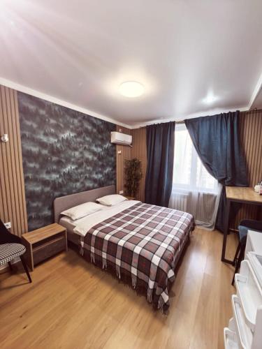 una camera da letto con un letto con una coperta scozzese di ZhanHotels a Almaty