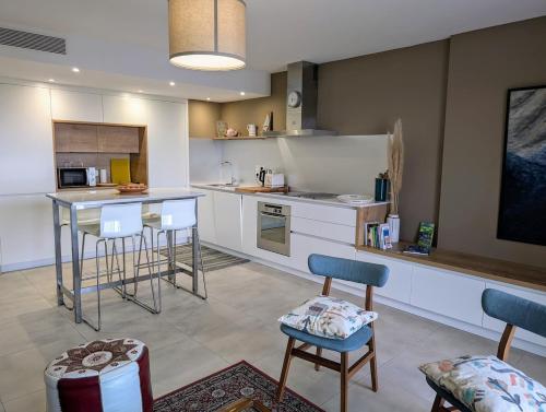 une cuisine avec des armoires blanches et des tabourets de bar dans l'établissement MILLESIME 5202 : Belle vue proche du port, élégant avec parking, à Marseillan