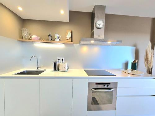- une cuisine avec des placards blancs, un évier et une horloge dans l'établissement MILLESIME 5202 : Belle vue proche du port, élégant avec parking, à Marseillan