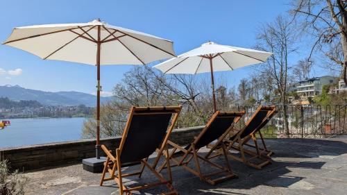 a group of chairs and umbrellas sitting next to a lake at Charming house with a lake view in Luzern