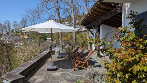 a group of chairs and an umbrella on a patio at Charming house with a lake view in Luzern