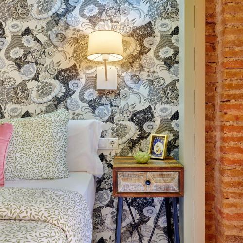 a bedroom with a bed and a side table with a lamp at Zirí Suites - Hostatel in Granada