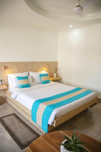 a bedroom with a large bed with blue and white pillows at Hotel Lake Shilloi in Dimāpur
