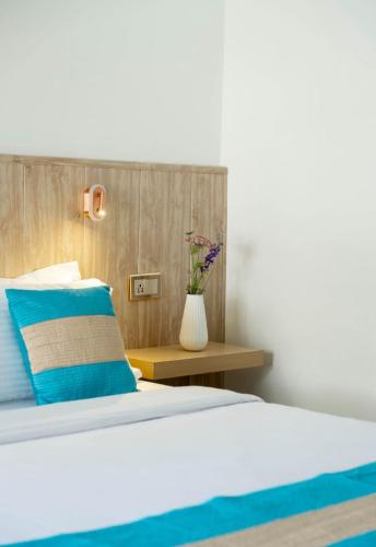a bed with a blue pillow and a vase with flowers at Hotel Lake Shilloi in Dimāpur