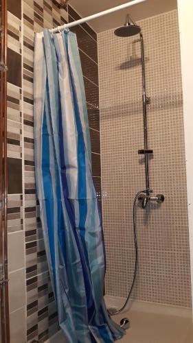La salle de bains est pourvue d'une douche avec un rideau de douche bleu et blanc. dans l'établissement Maison de vacances proximité bord de mer, à Canet