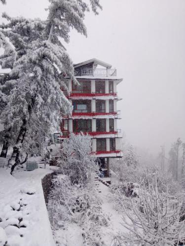 a snow covered building in front of a tree at Hotel Sudrishya in Kīar