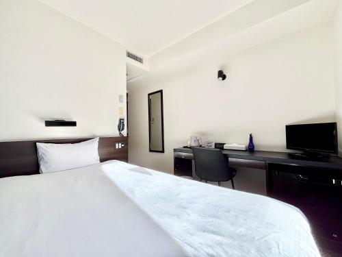 a bedroom with a bed and a desk with a computer at Hotel Bougain Villea Sapporo in Sapporo