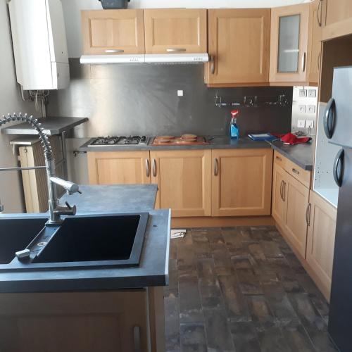 une cuisine avec des armoires en bois et un évier dans l'établissement T4 chaleureux en plein centre, à Clermont-Ferrand